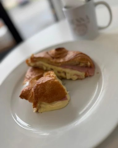 Flaky ham and cheese croissant on a white plate